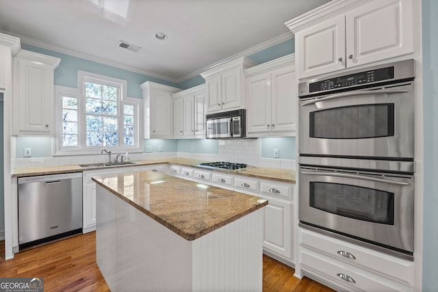 kitchen featuring appliances with stainless steel finishes, white cabinets, and a sink