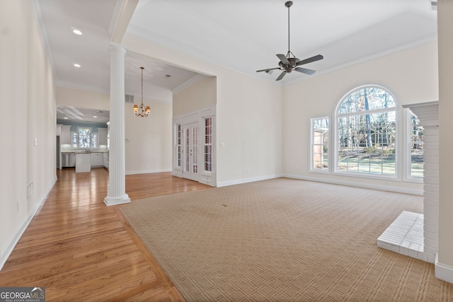 unfurnished living room featuring crown molding, decorative columns, and a healthy amount of sunlight