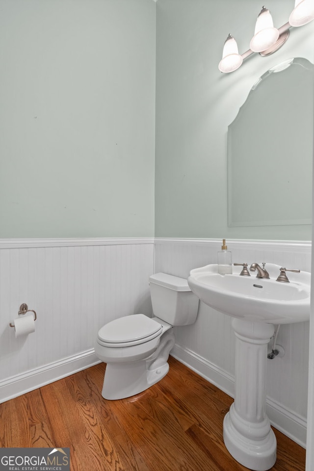 half bath featuring toilet, a wainscoted wall, and wood finished floors