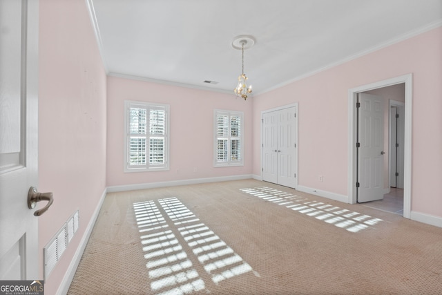 empty room with an inviting chandelier, visible vents, carpet flooring, and ornamental molding