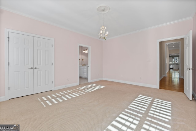 unfurnished bedroom featuring carpet floors, crown molding, baseboards, and a notable chandelier