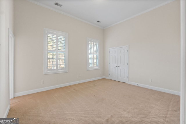 carpeted spare room featuring baseboards, visible vents, and crown molding