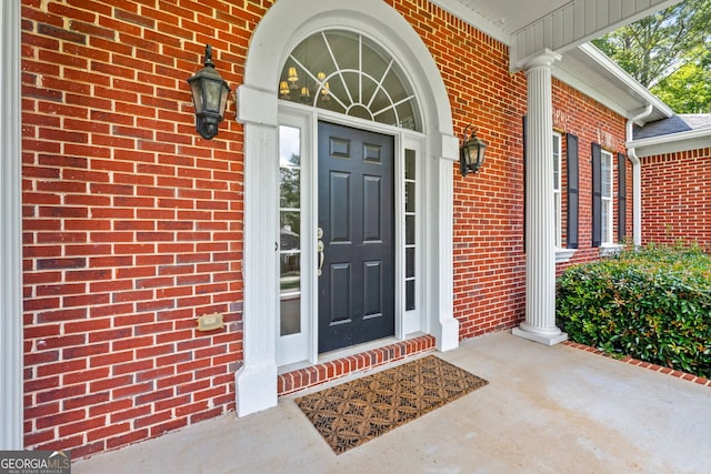 view of exterior entry featuring a porch and brick siding