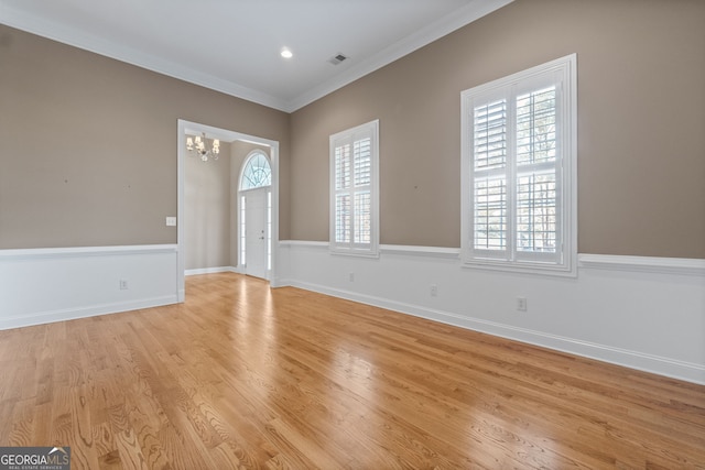 interior space featuring visible vents, baseboards, ornamental molding, light wood-style floors, and a chandelier