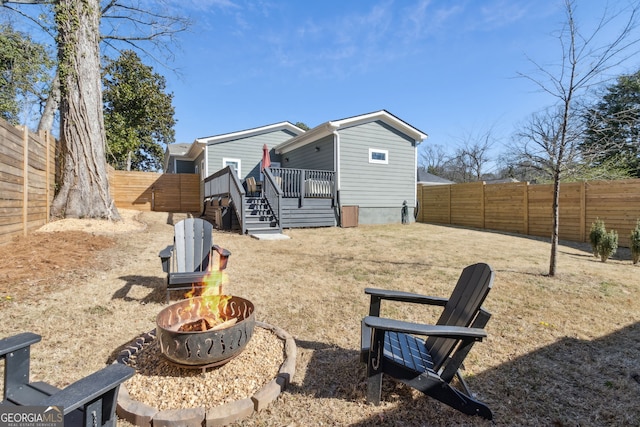 rear view of property featuring an outdoor fire pit, a fenced backyard, and a wooden deck