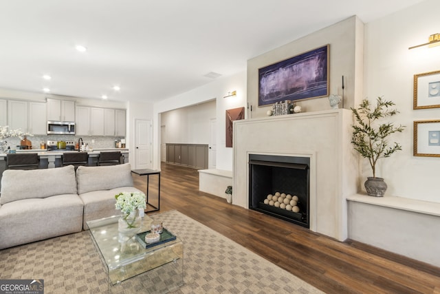 living area featuring a fireplace, visible vents, dark wood-style flooring, and recessed lighting