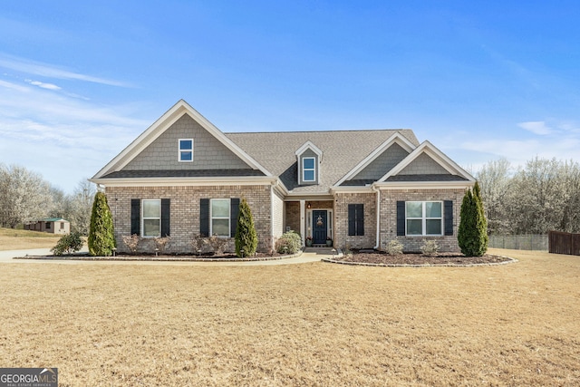 craftsman inspired home featuring brick siding, a front yard, and fence