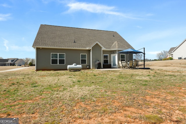 rear view of house with a patio area, a shingled roof, and a yard