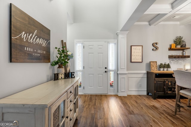 foyer entrance with beam ceiling, coffered ceiling, wood finished floors, and decorative columns