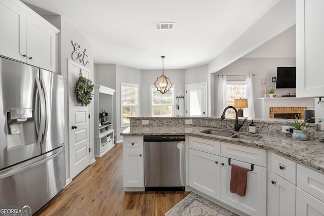 kitchen featuring wood finished floors, a sink, visible vents, white cabinetry, and appliances with stainless steel finishes