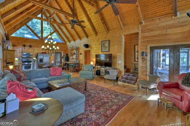 living room with ceiling fan with notable chandelier, wood walls, wood ceiling, beam ceiling, and light wood finished floors
