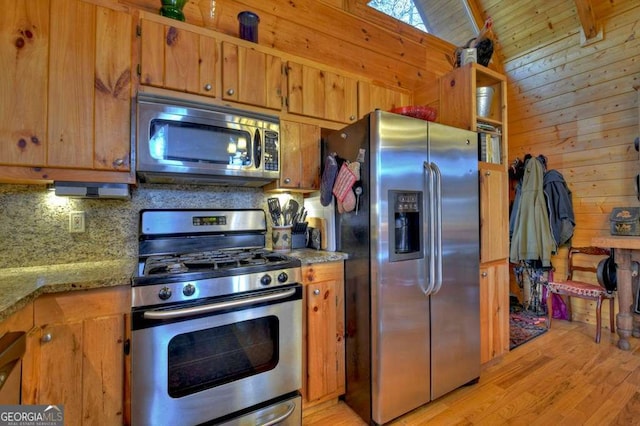 kitchen with wooden walls, decorative backsplash, brown cabinets, stainless steel appliances, and light wood-style floors