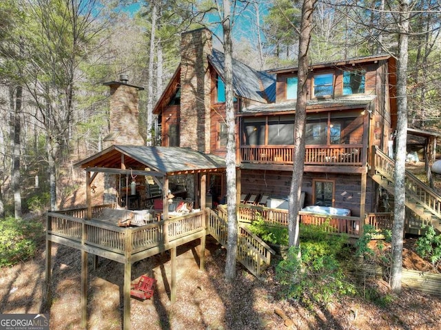 back of property featuring stairway, a sunroom, a chimney, and a wooden deck