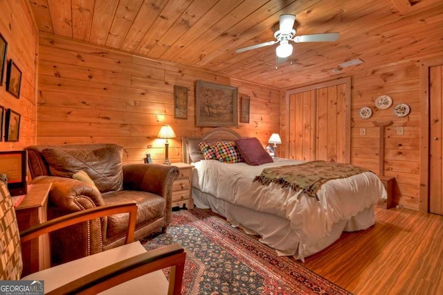 bedroom featuring a ceiling fan, wood finished floors, wood ceiling, and wooden walls