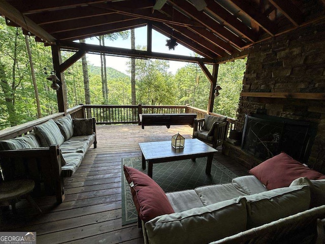 exterior space with an outdoor stone fireplace, vaulted ceiling, and a view of trees