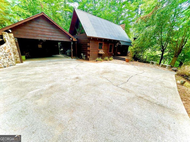 view of side of property with metal roof and driveway