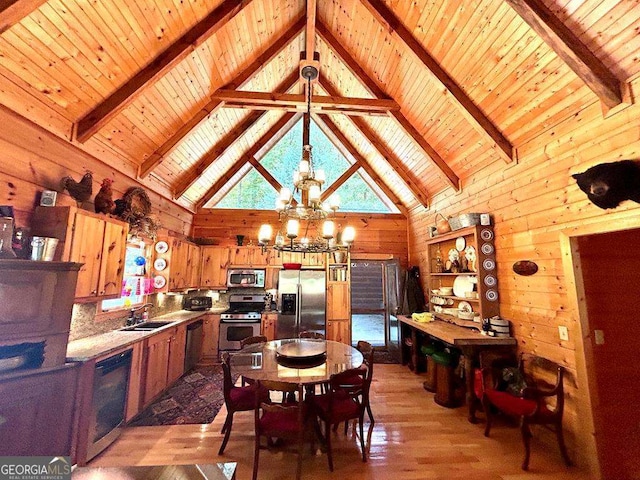 dining area with a chandelier, wood walls, beamed ceiling, and light wood finished floors