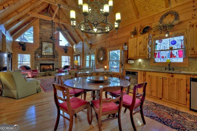 dining space featuring light wood-style floors, wood ceiling, wooden walls, and a stone fireplace