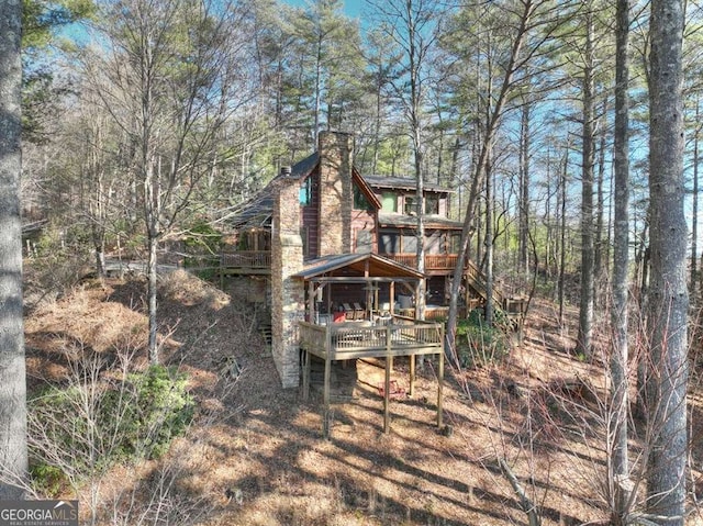 back of house featuring a chimney and a wooden deck