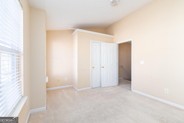 unfurnished bedroom with lofted ceiling, carpet floors, and baseboards