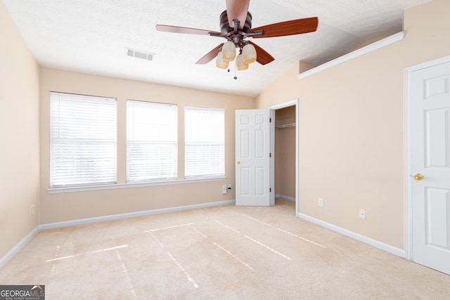 unfurnished bedroom featuring lofted ceiling, a textured ceiling, carpet floors, visible vents, and baseboards