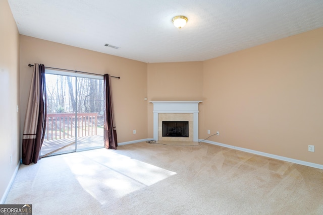 unfurnished living room featuring light colored carpet, baseboards, visible vents, and a tiled fireplace