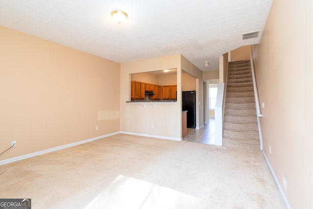 unfurnished living room featuring visible vents, light carpet, baseboards, and stairs