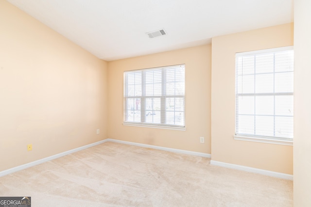 carpeted spare room with visible vents, plenty of natural light, and baseboards