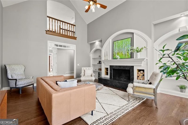 living area featuring built in features, a high end fireplace, dark wood finished floors, and baseboards