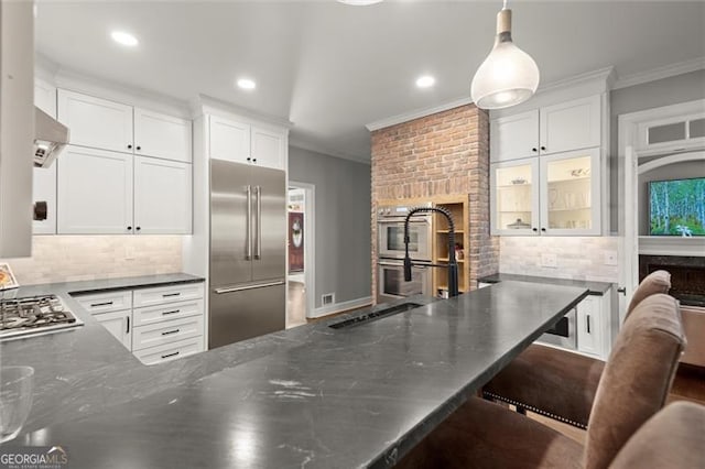 kitchen featuring ornamental molding, appliances with stainless steel finishes, a fireplace, and white cabinetry