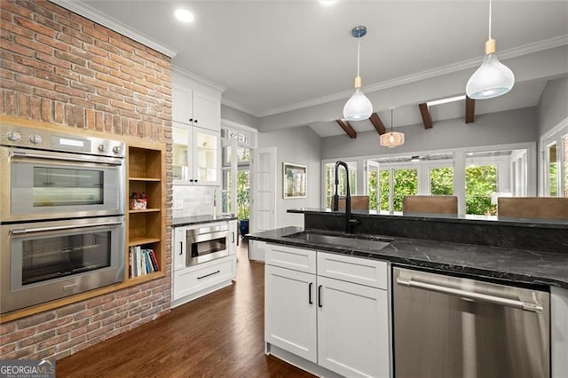 kitchen featuring decorative light fixtures, appliances with stainless steel finishes, dark wood-type flooring, white cabinets, and a sink