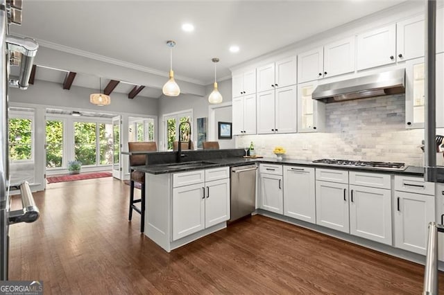 kitchen featuring dark countertops, appliances with stainless steel finishes, a peninsula, under cabinet range hood, and a sink