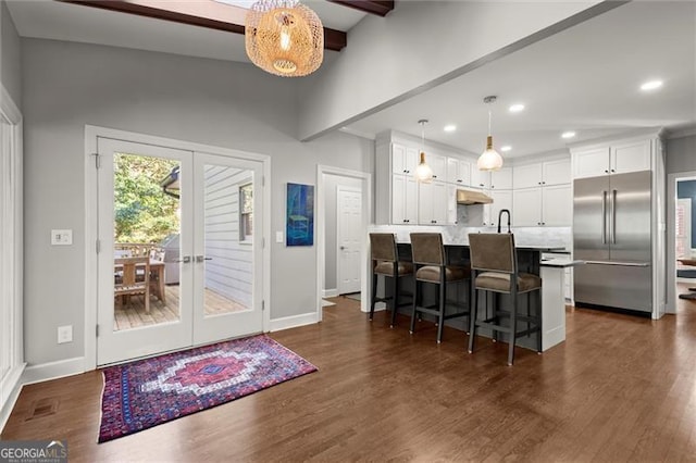 kitchen featuring dark wood finished floors, built in refrigerator, french doors, white cabinetry, and beam ceiling