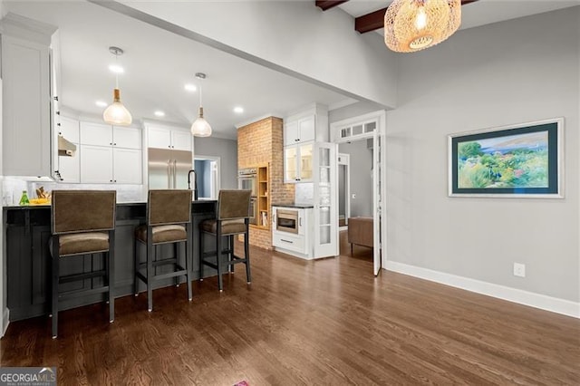 kitchen with built in appliances, a peninsula, tasteful backsplash, and white cabinetry