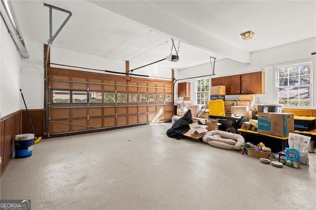 garage featuring wooden walls, wainscoting, and a garage door opener