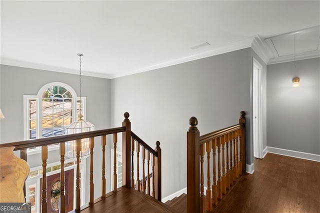 hall featuring attic access, baseboards, ornamental molding, wood finished floors, and an upstairs landing