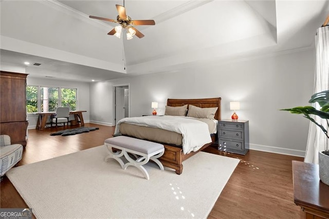 bedroom featuring ceiling fan, baseboards, a raised ceiling, and wood finished floors