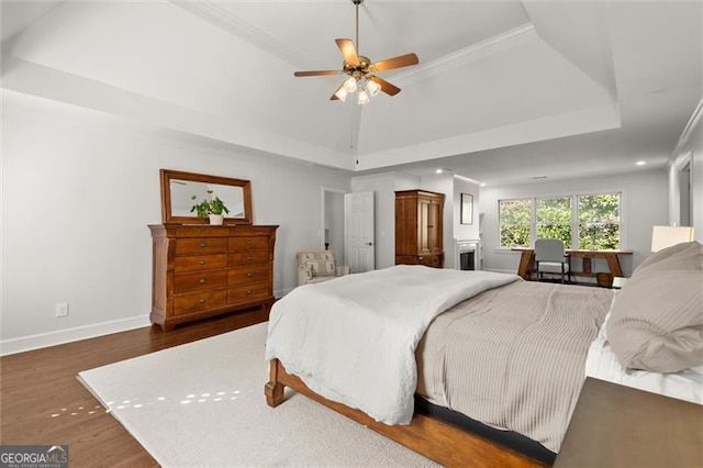 bedroom with baseboards, a tray ceiling, ceiling fan, and wood finished floors