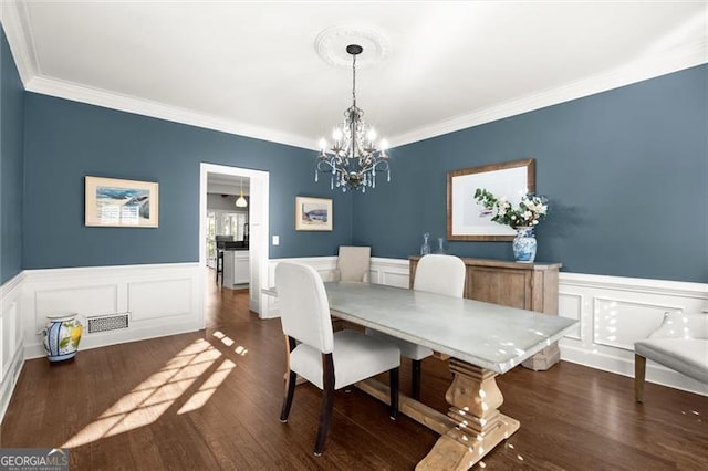 dining room with a wainscoted wall, visible vents, ornamental molding, dark wood finished floors, and an inviting chandelier