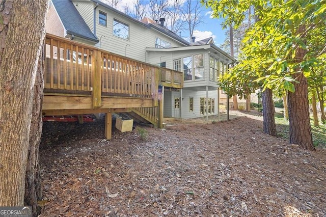 back of house with a shingled roof and a wooden deck