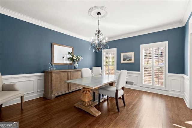 dining space featuring ornamental molding, dark wood-type flooring, a wainscoted wall, and an inviting chandelier