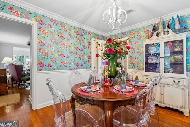 dining room with wallpapered walls, wood-type flooring, a chandelier, and a wainscoted wall