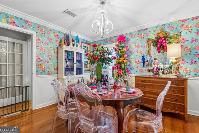 dining room with a chandelier, a wainscoted wall, wood finished floors, visible vents, and wallpapered walls