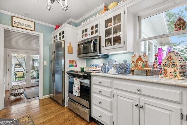 kitchen with white cabinets, glass insert cabinets, stainless steel appliances, crown molding, and light wood-type flooring