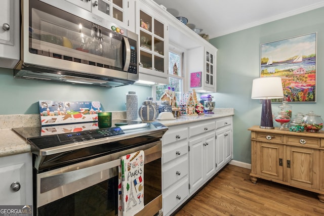 kitchen with glass insert cabinets, appliances with stainless steel finishes, crown molding, light wood-style floors, and white cabinetry