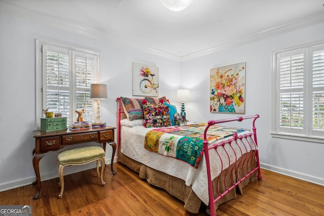 bedroom with ornamental molding, baseboards, and wood finished floors