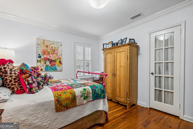 bedroom featuring wood finished floors, visible vents, and crown molding