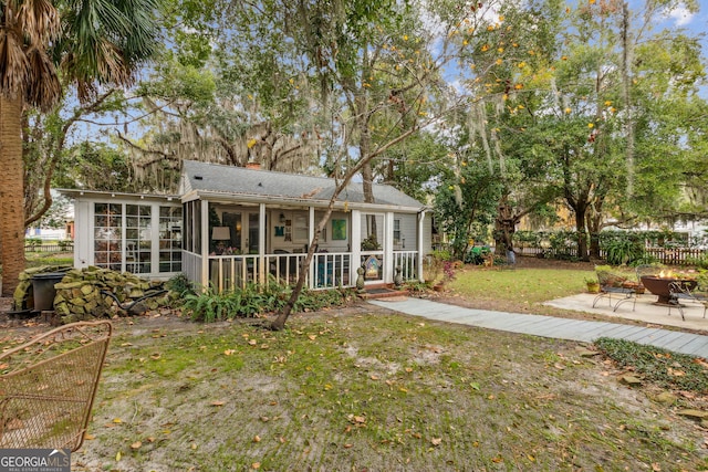 rear view of property with a lawn, a sunroom, a chimney, fence, and a patio area