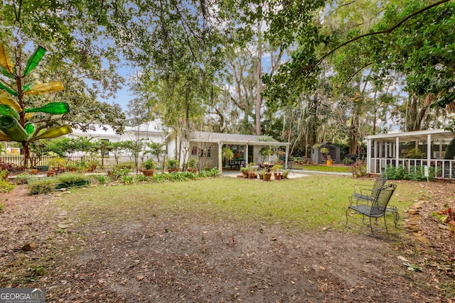 view of yard with a storage unit, an outdoor structure, fence, and a sunroom