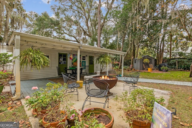 view of patio / terrace featuring a fire pit, a storage unit, and an outbuilding